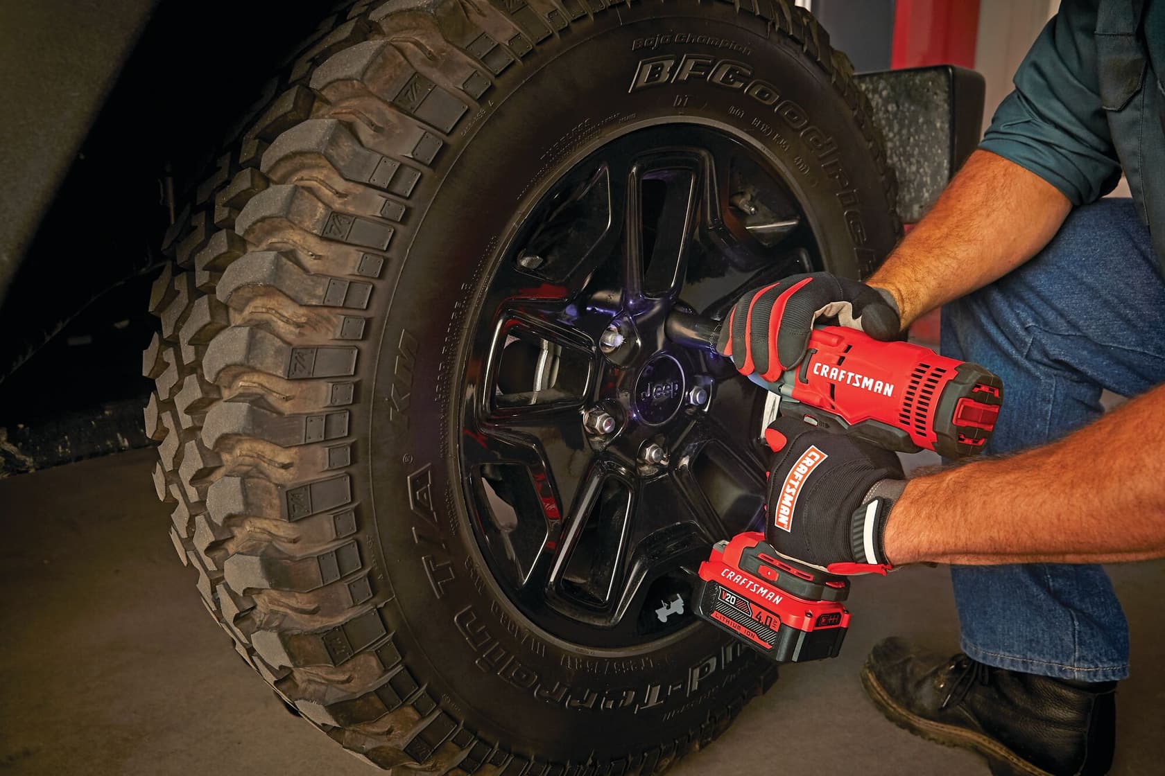 Photo of Craftsman cordless impact wrench CMCF900M1 used on Jeep tire, red and black tool with gloves.