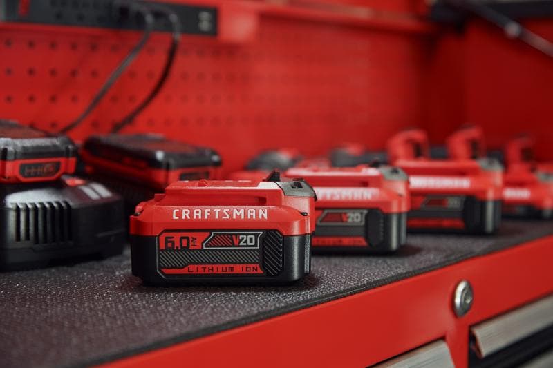 Photo de batterie lithium-ion Craftsman V20 CMCB206, 6.0Ah, rouge et noire, sur établi.