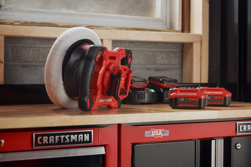 Photographie de polisseuse sans fil Craftsman CMCE100B rouge et noire sur table d’atelier, batteries visibles.