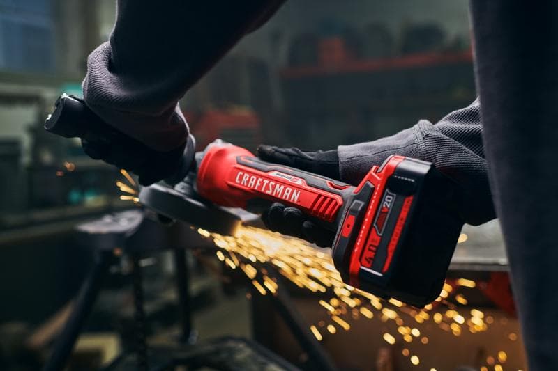 Photo de la meuleuse sans fil Craftsman SKU CMCG451B en utilisation, corps rouge et noir, étincelles, atelier en arrière-plan.