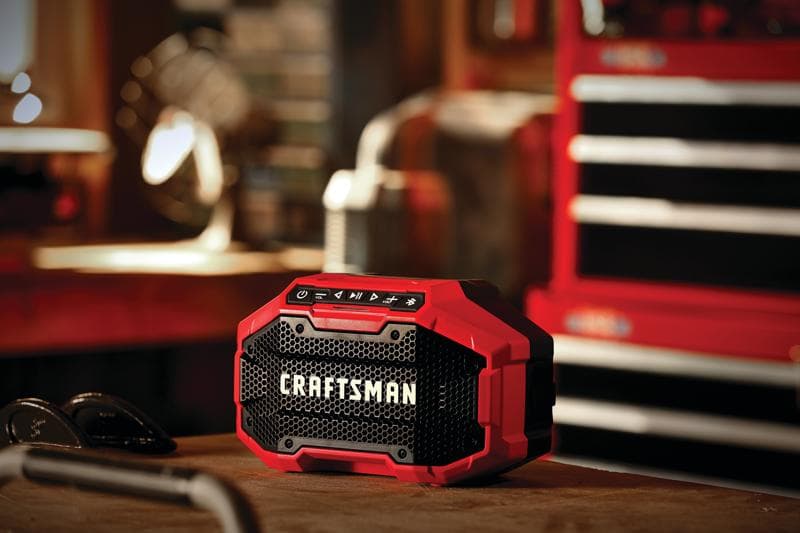 Photo du haut-parleur Bluetooth portable Craftsman CMCR001B rouge et noir sur un établi dans un atelier.