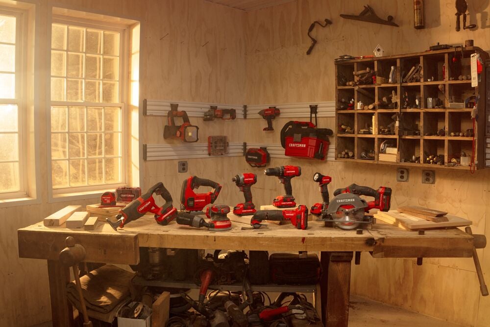 Photo of Craftsman CMCK800D2 power tool set on a workshop table, red and black tools with wood and storage shelves.
