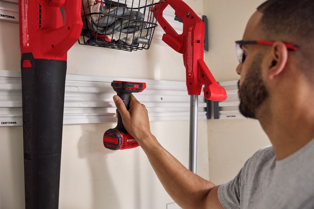 Photo d'une personne utilisant une perceuse sans fil Craftsman CMCF801 dans un garage avec rangement mural organisé.