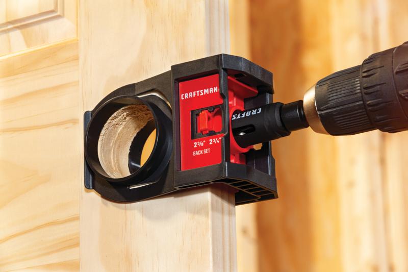 Photo of Craftsman door lock installation kit CMAH1MDL in use on a wooden door with a drill attached.