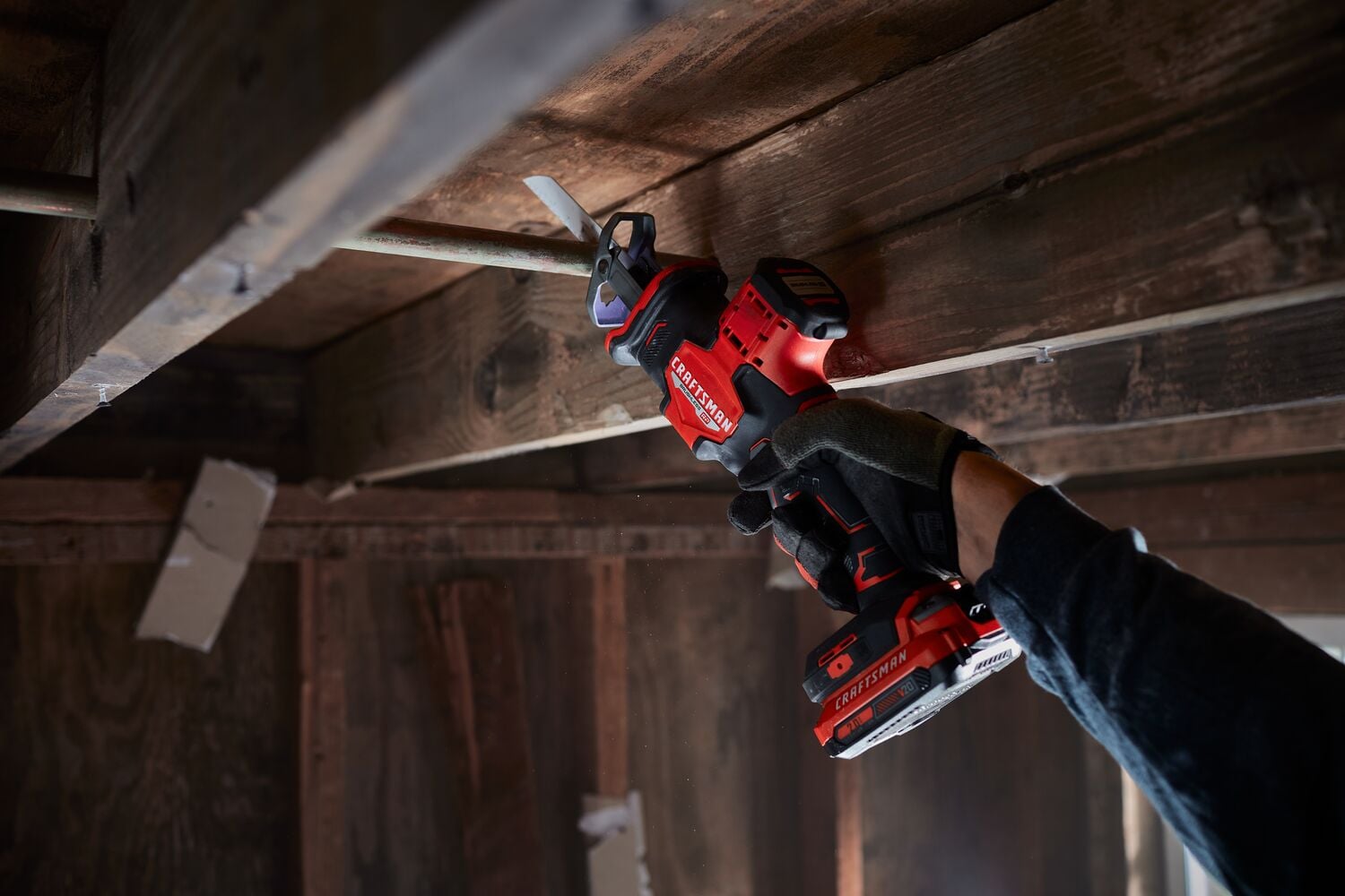Photo of Craftsman cordless reciprocating saw CMCS340B used to cut metal pipe in a wooden ceiling.