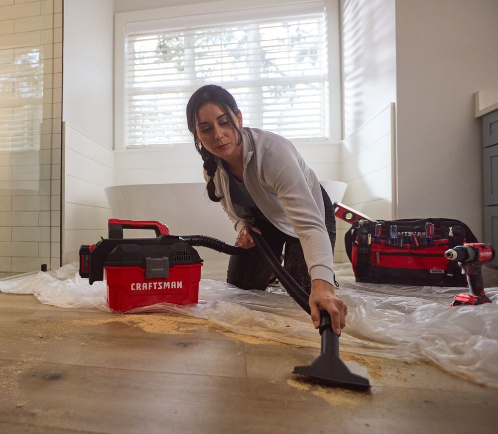 Photo of Craftsman portable vacuum CMCV002B cleaning sawdust from floor, next to Craftsman tool bag and drill.