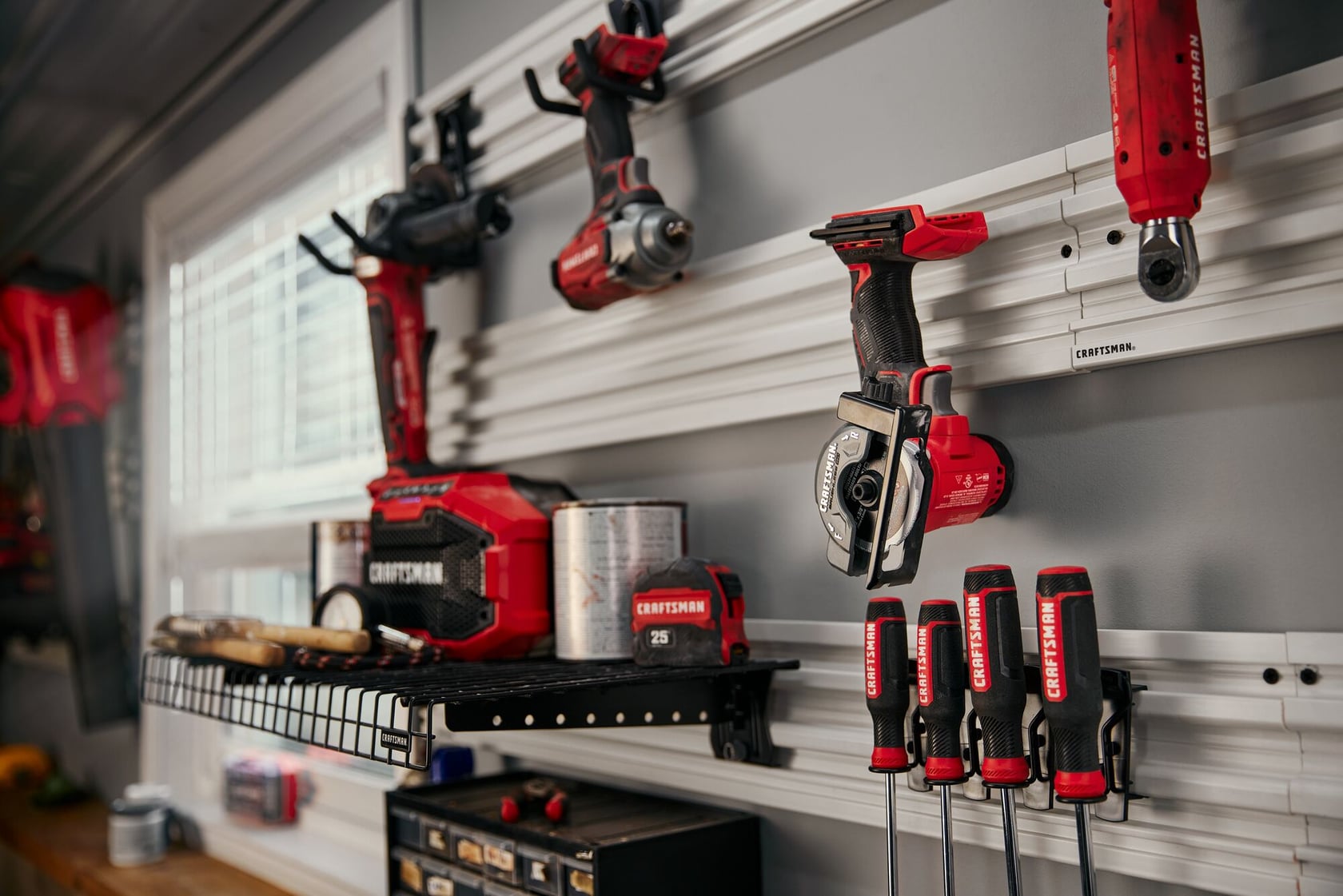 Outils électriques et manuels Craftsman CMCM300B rouges et noirs sur un organisateur mural dans un atelier.