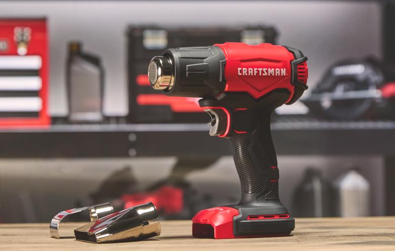 Photo du pistolet à air chaud sans fil Craftsman CMCE530B avec deux embouts métalliques sur une table, design rouge et noir.