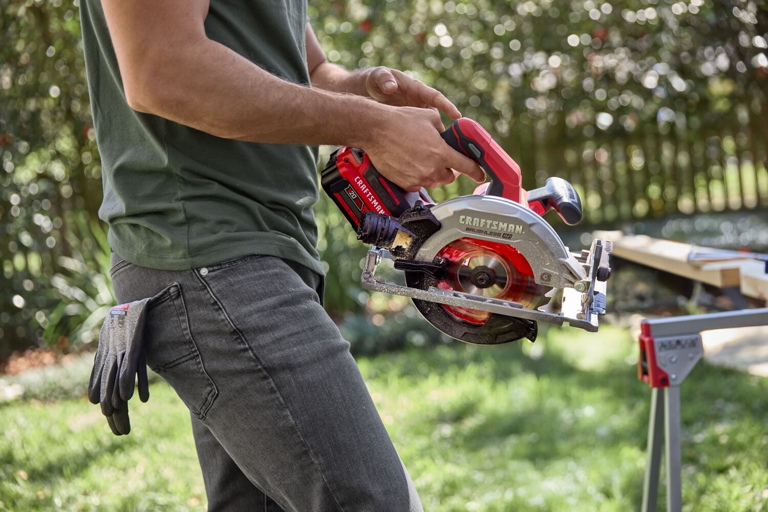 Photo of Craftsman CMCS551B cordless circular saw held outdoors by person, red and silver design.