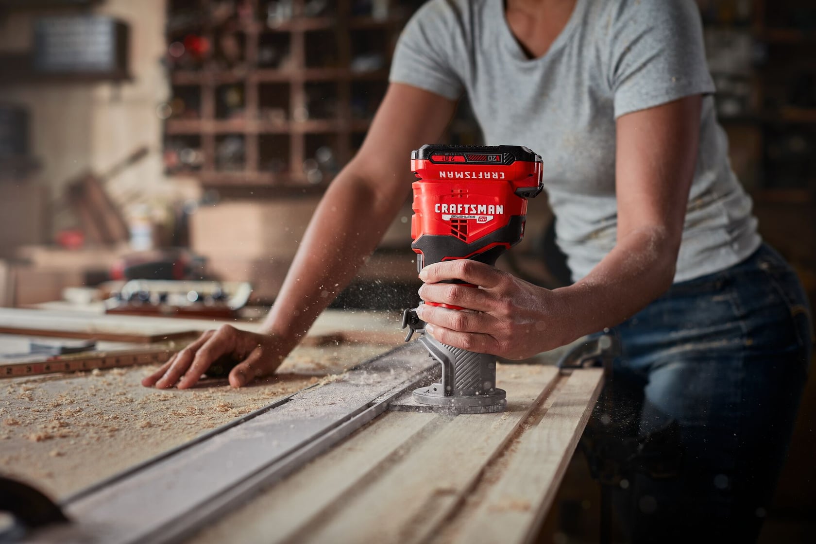 Photographie d'une personne utilisant une défonceuse portative Craftsman, SKU CMCW400B, sur une planche en bois dans un atelier.