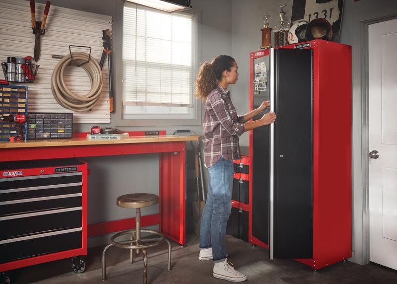 32 inch Wide freestanding tall garage storage cabinet being used by a person to keep items.