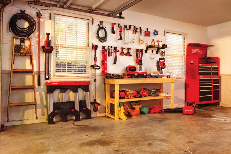 Multiple tools and gear mounted on Versa Track 5 and 5 tenths inch White Composite Multipurpose Storage Rail System installed on wall of a workshop.