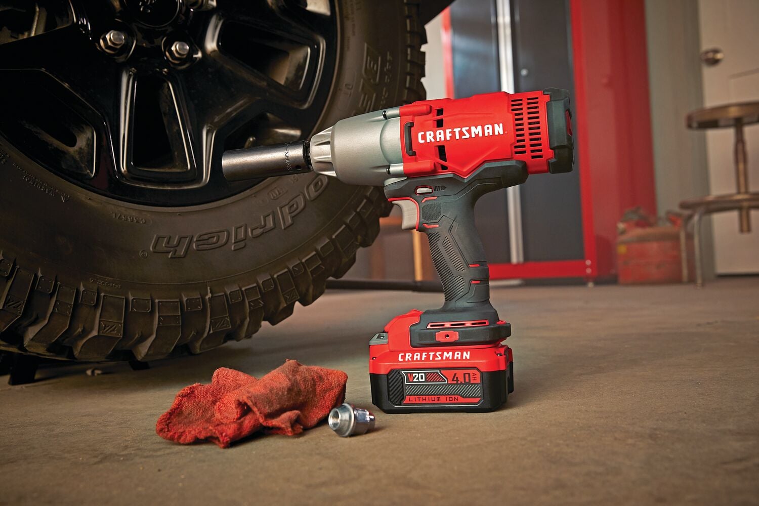 Cordless half inch impact wrench kit 1 battery placed on ground next to car tyre.