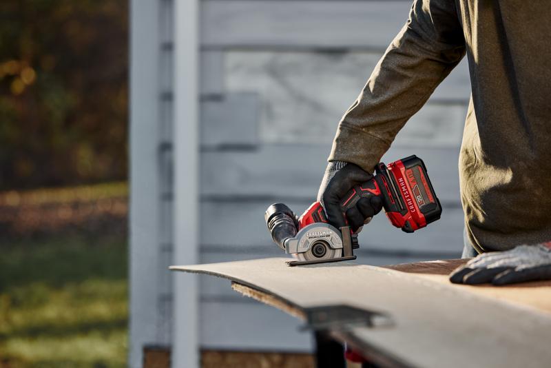Photo d'une personne utilisant une scie compacte Craftsman CMCM300B pour couper une plaque à l'extérieur.