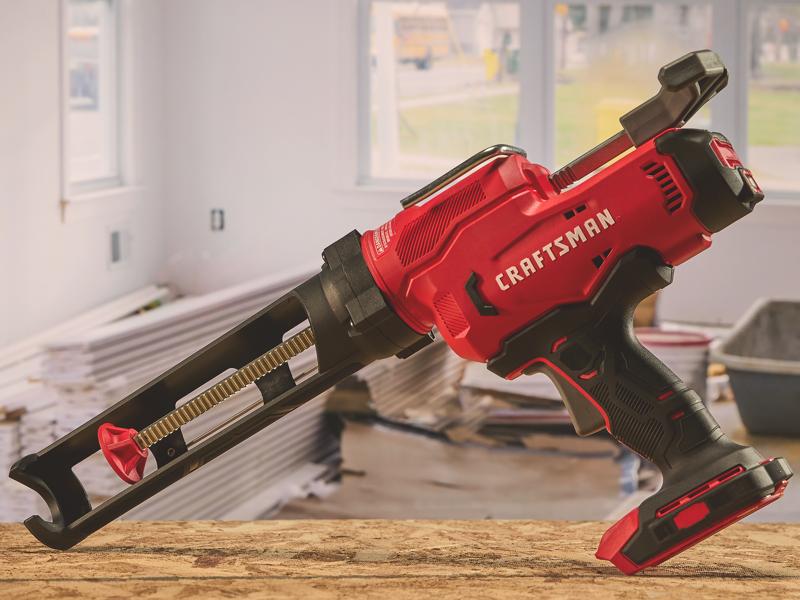 Photo du pistolet à calfeutrer sans fil Craftsman, SKU CMCE600, rouge et noir, posé sur une table dans un atelier.