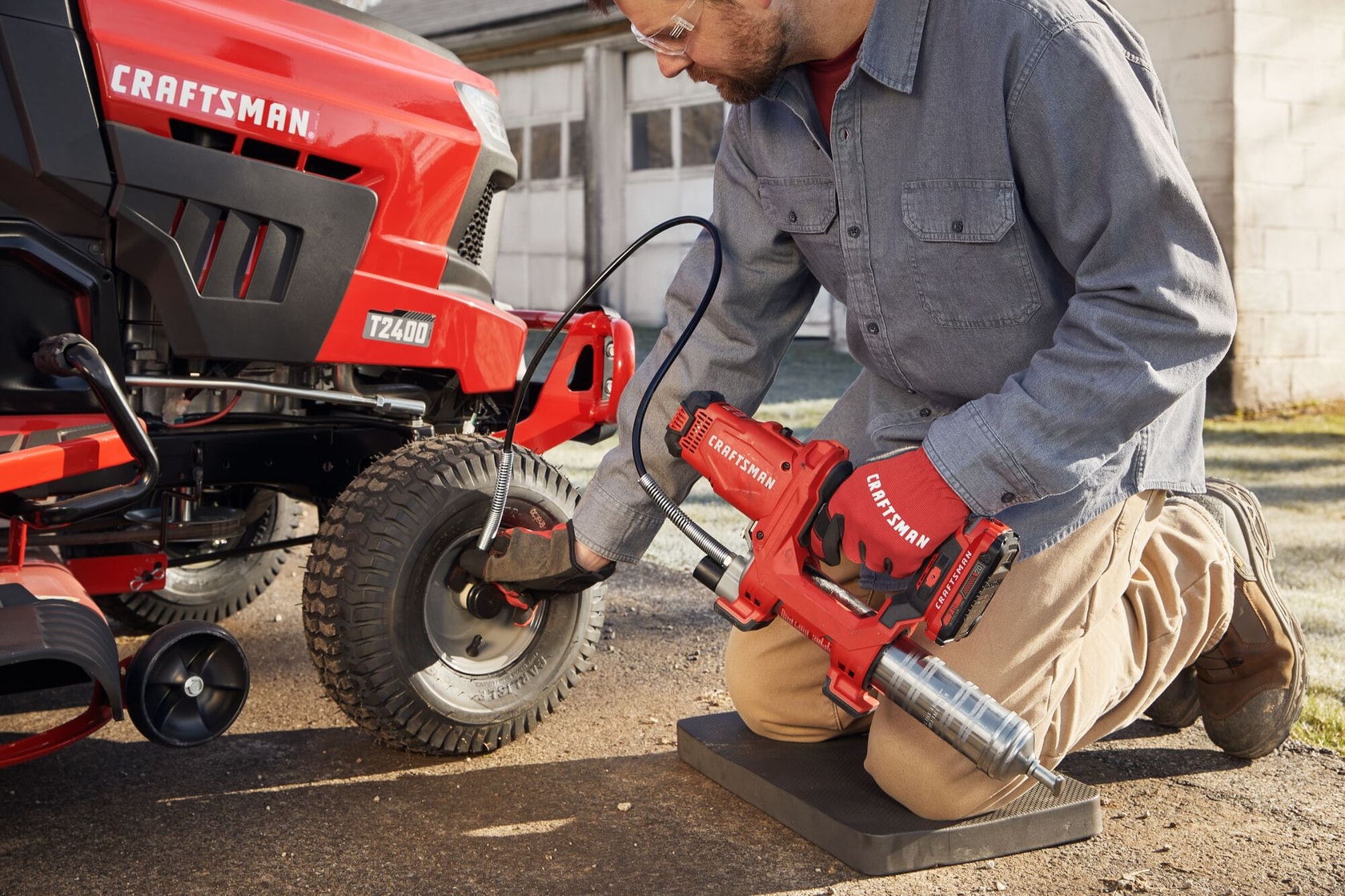 Photo of end-user applying grease with grease gun to farm equipment.