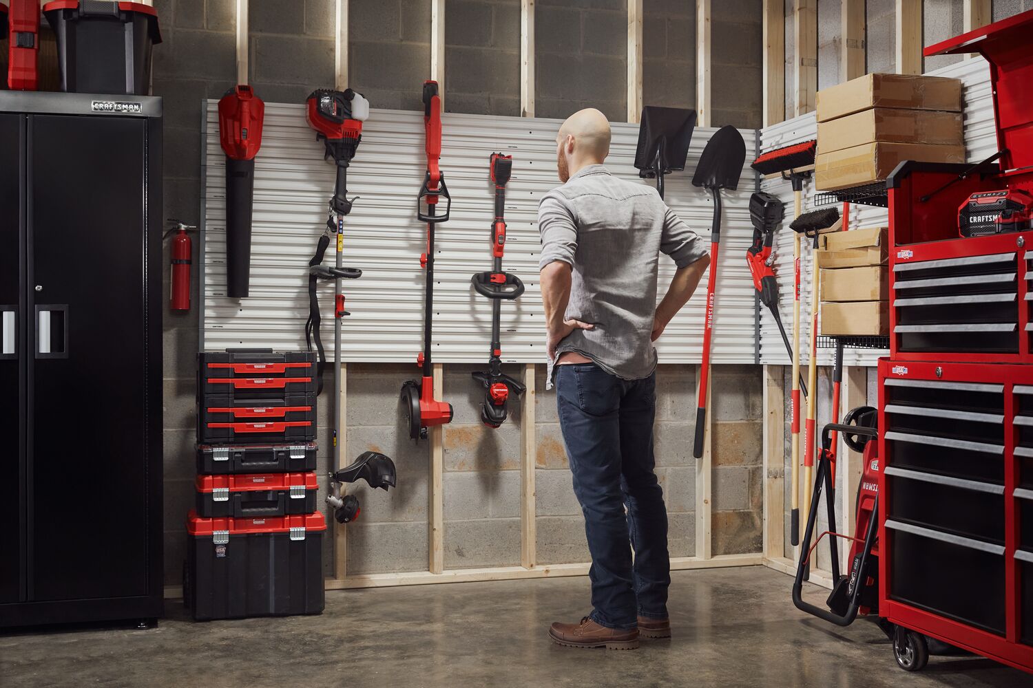 Man standing admiring his garage filled with power tools, storage, outdoor products