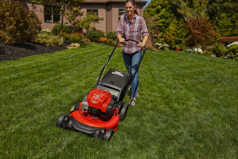 CRAFTSMAN M125 Push Mower mowing the grass in the backyard in front view in plaid shirt
