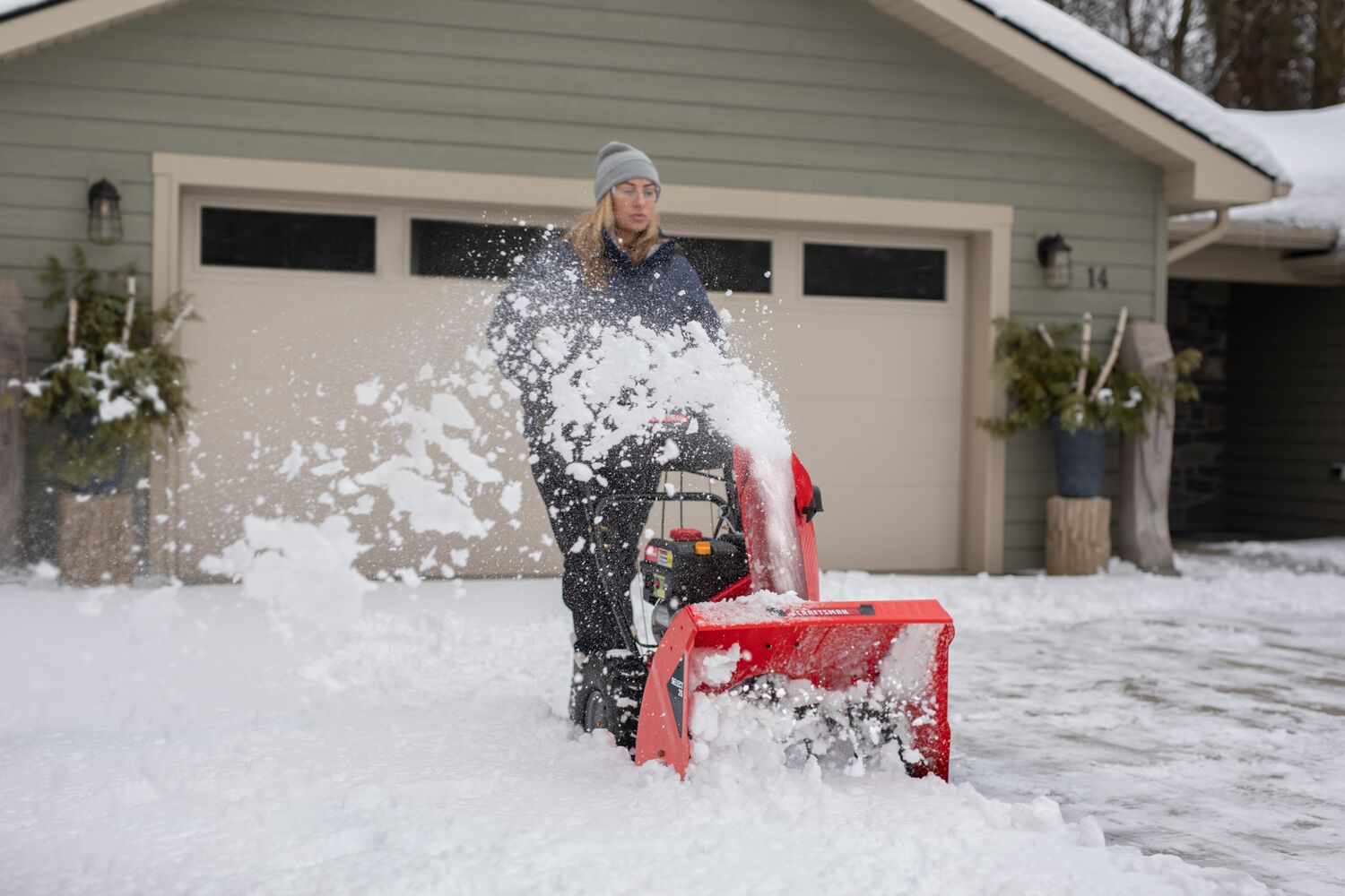SELECT 26 inch 243 CC two stage gas snow blower with push button electric start being used by a person.