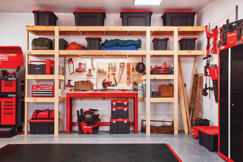Various tools and gadgets mounted on Versa Track 5 and 5 tenths inch White Composite Multipurpose Storage Rail System installed on wall of garage containing tools cabinets and storage chests stacked on wooden racks.