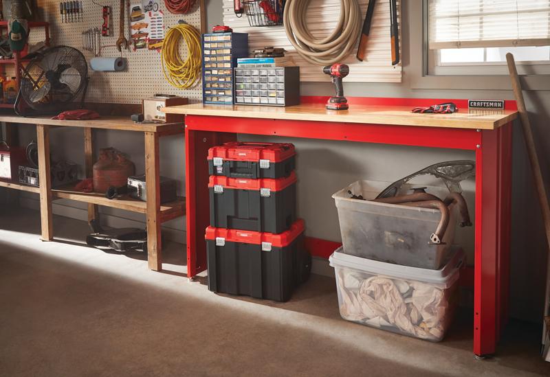 6 foot wide Workbench with Butcher Block Top having tools and storage boxes on its top placed on ground in a garage workshop.