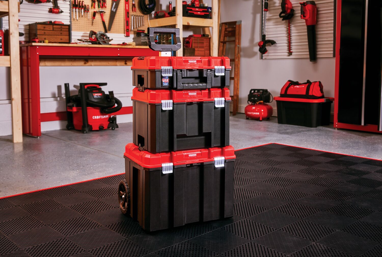 Various tools mounted on Versa Track 5 and 5 tenths inch White Composite Multipurpose Storage Rail System installed on wall while three tiered mobile tool chest rests on floor.