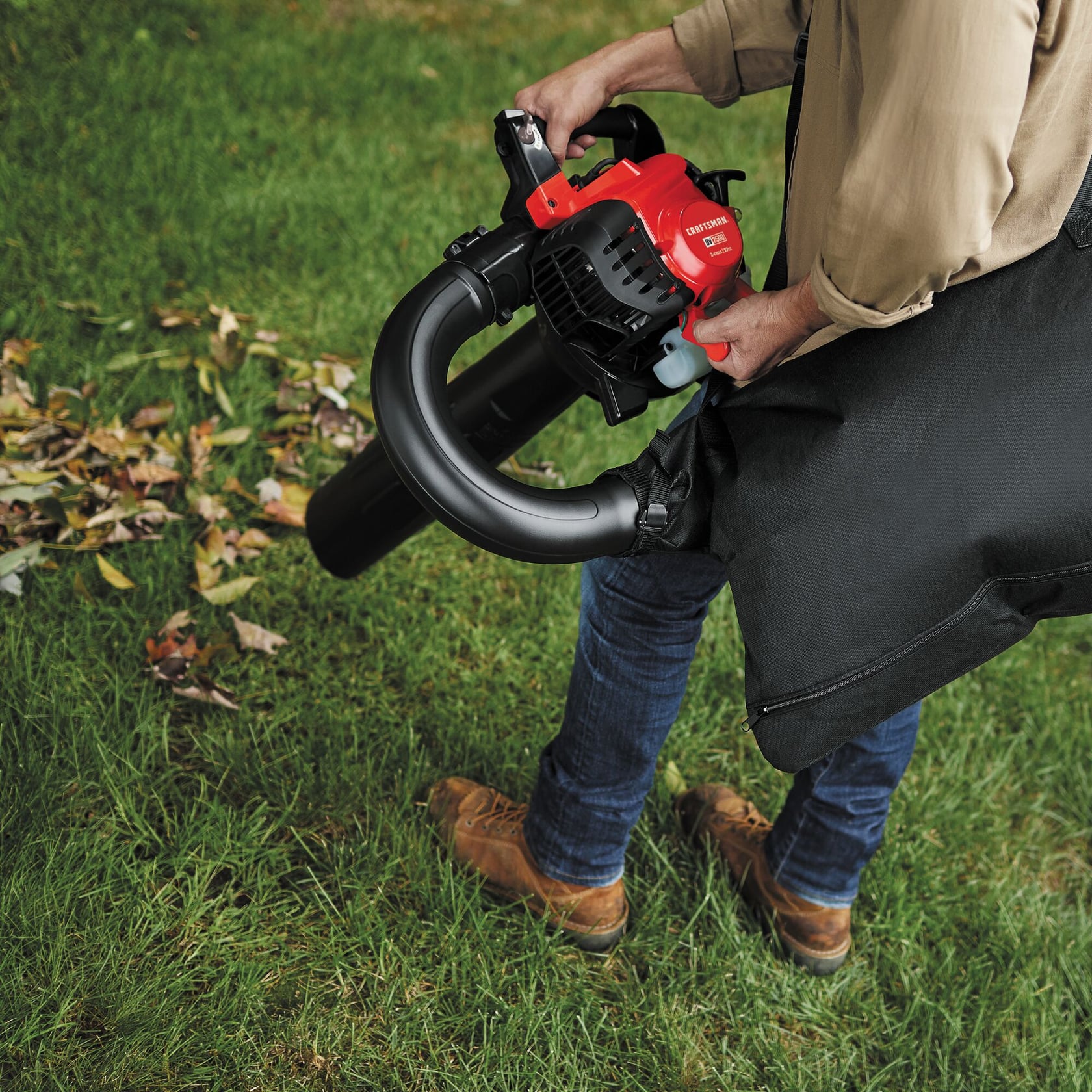 Photo of a person using a CRAFTSMAN leaf blower vacuum, SKU CMXGAAMRBV27, collecting leaves on grass.
