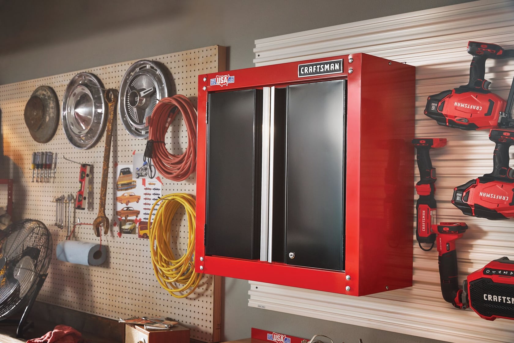 Armoire murale rouge Craftsman CMST22800RB avec portes noires dans un atelier, fixée au-dessus d’outils et équipements.