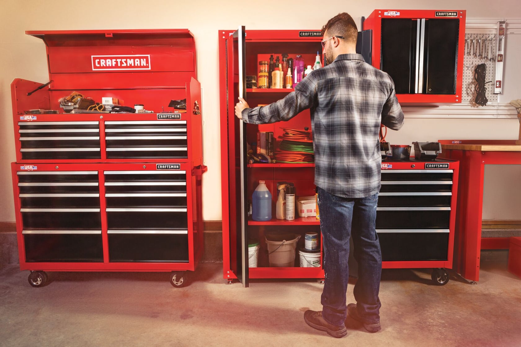 Photo of a man in a workshop with red Craftsman tool storage cabinets SKU CMST22800RB, showing drawers and shelves.