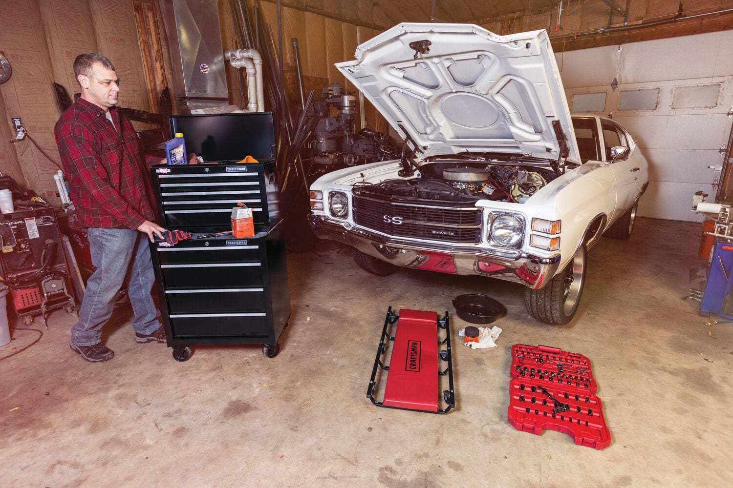Photo of Craftsman CMST22654BK black rolling tool chest with drawers in a garage, next to a classic white car with open hood.