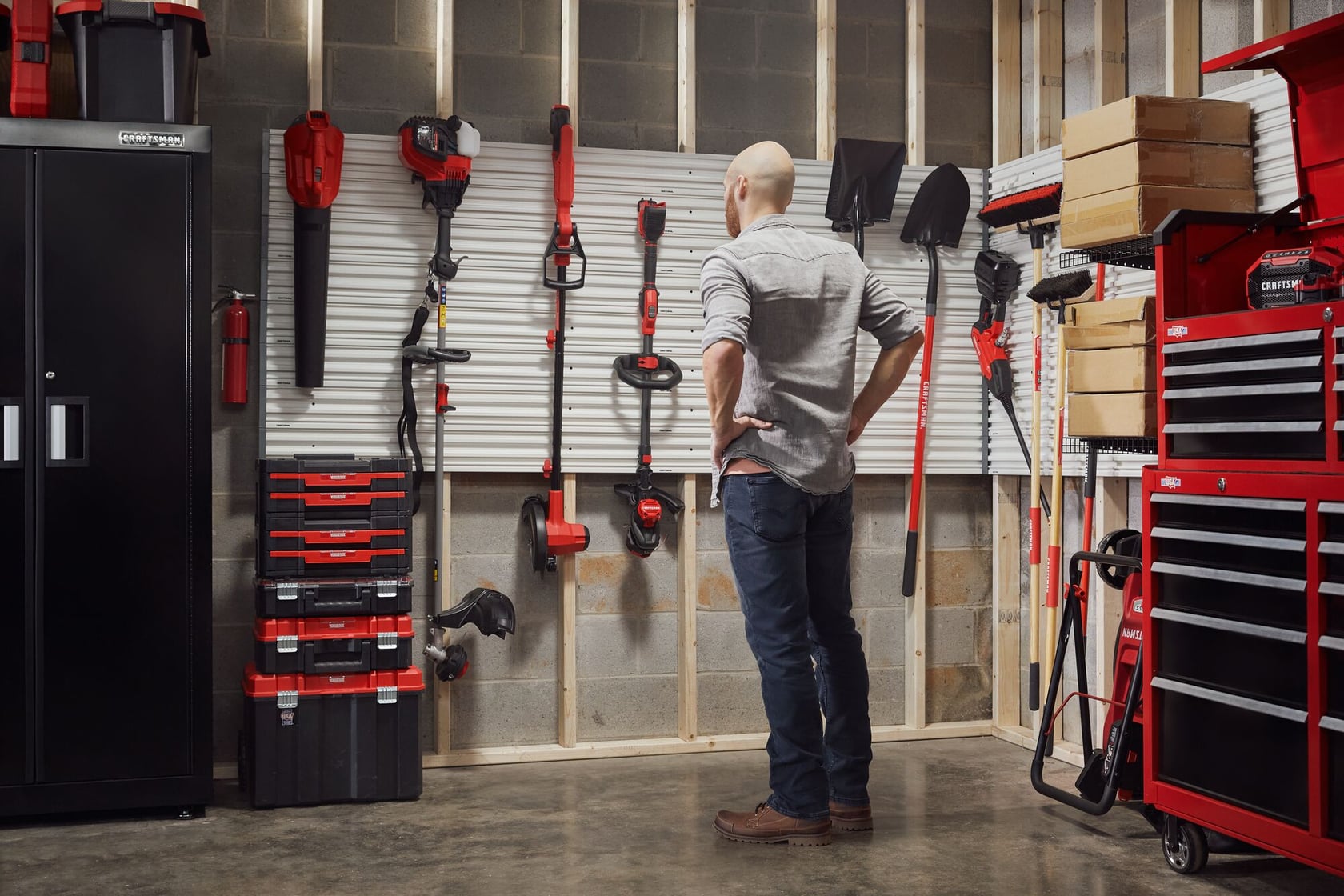 Man standing admiring his garage filled with power tools, storage, outdoor products