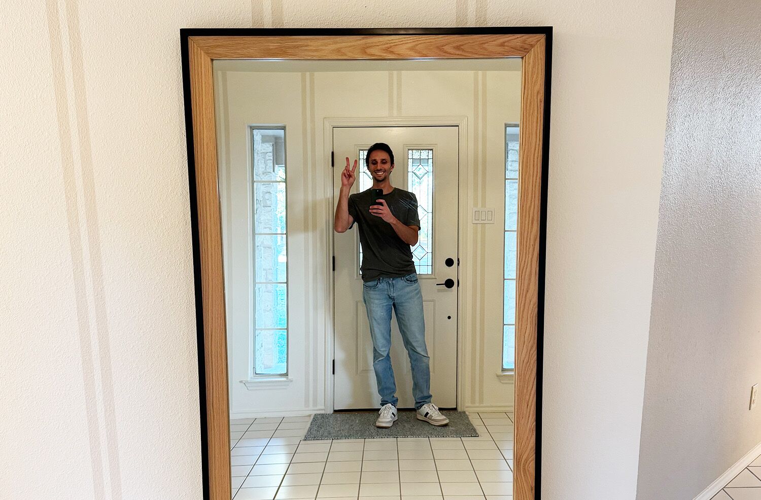 A couple takinga picture in a full length mirror with wooden edges