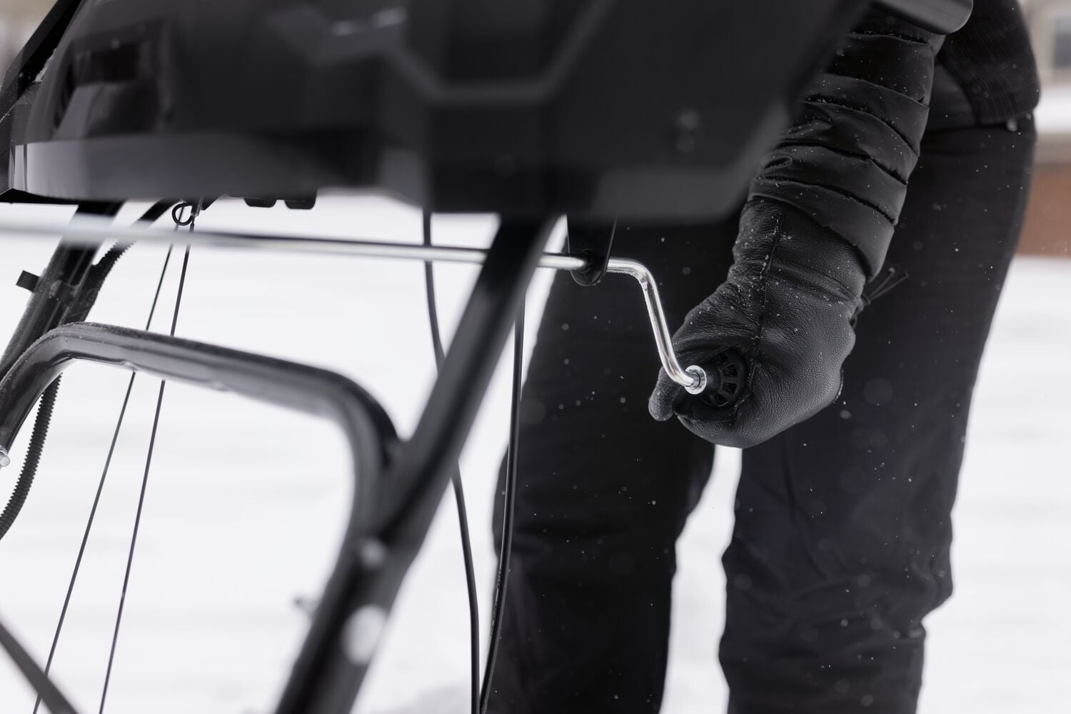 Gros plan d'une main gantée réglant la poignée de souffleuse à neige Craftsman en extérieur sur la neige, CMGB223101.