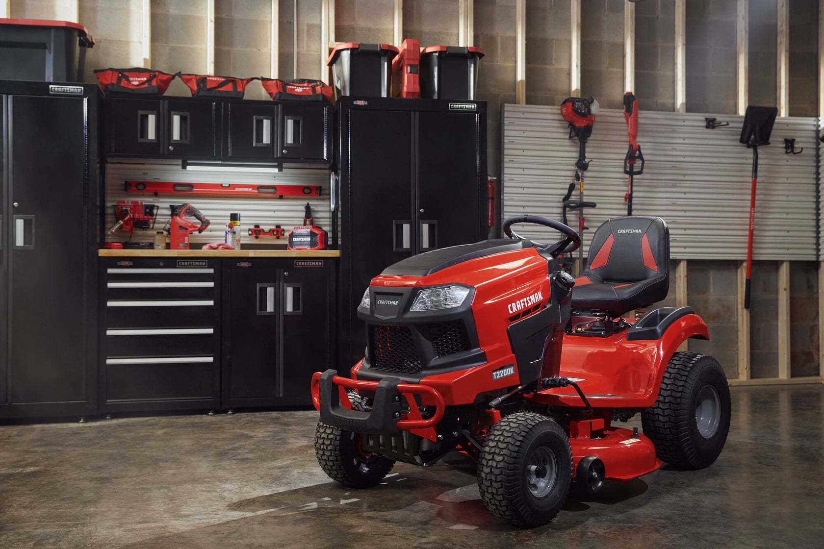 Photo of Craftsman red riding lawn mower CM13APA9ZSA93 in a garage with storage cabinets and tools.