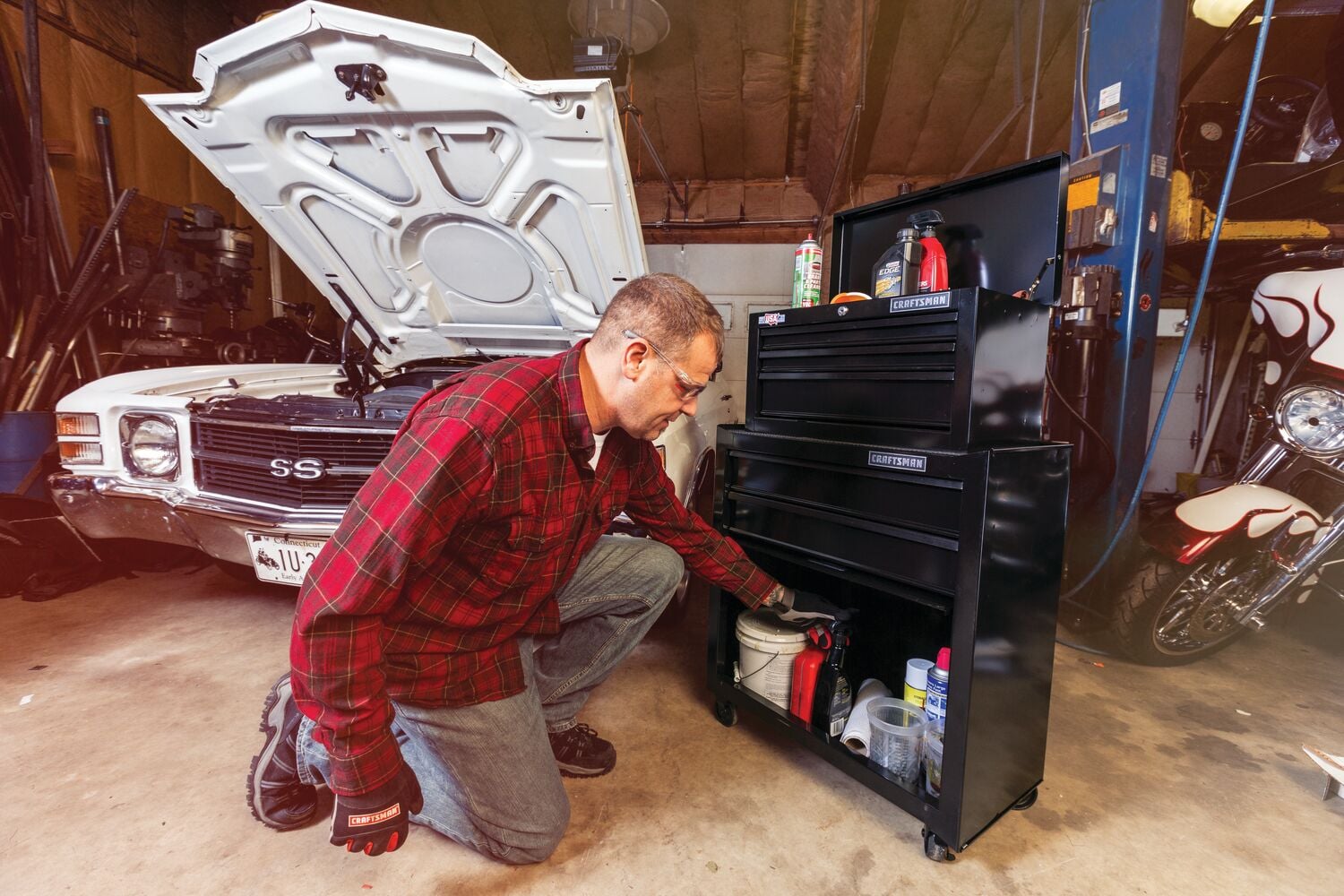 Photo of a person kneeling in front of a black Craftsman rolling tool chest, SKU CMST22653BK, in a garage setting.