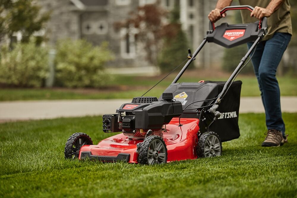 CRAFTSMAN M355 Self Propelled Lawn Mower close up in side view mowing lawn in green shirt and jeans