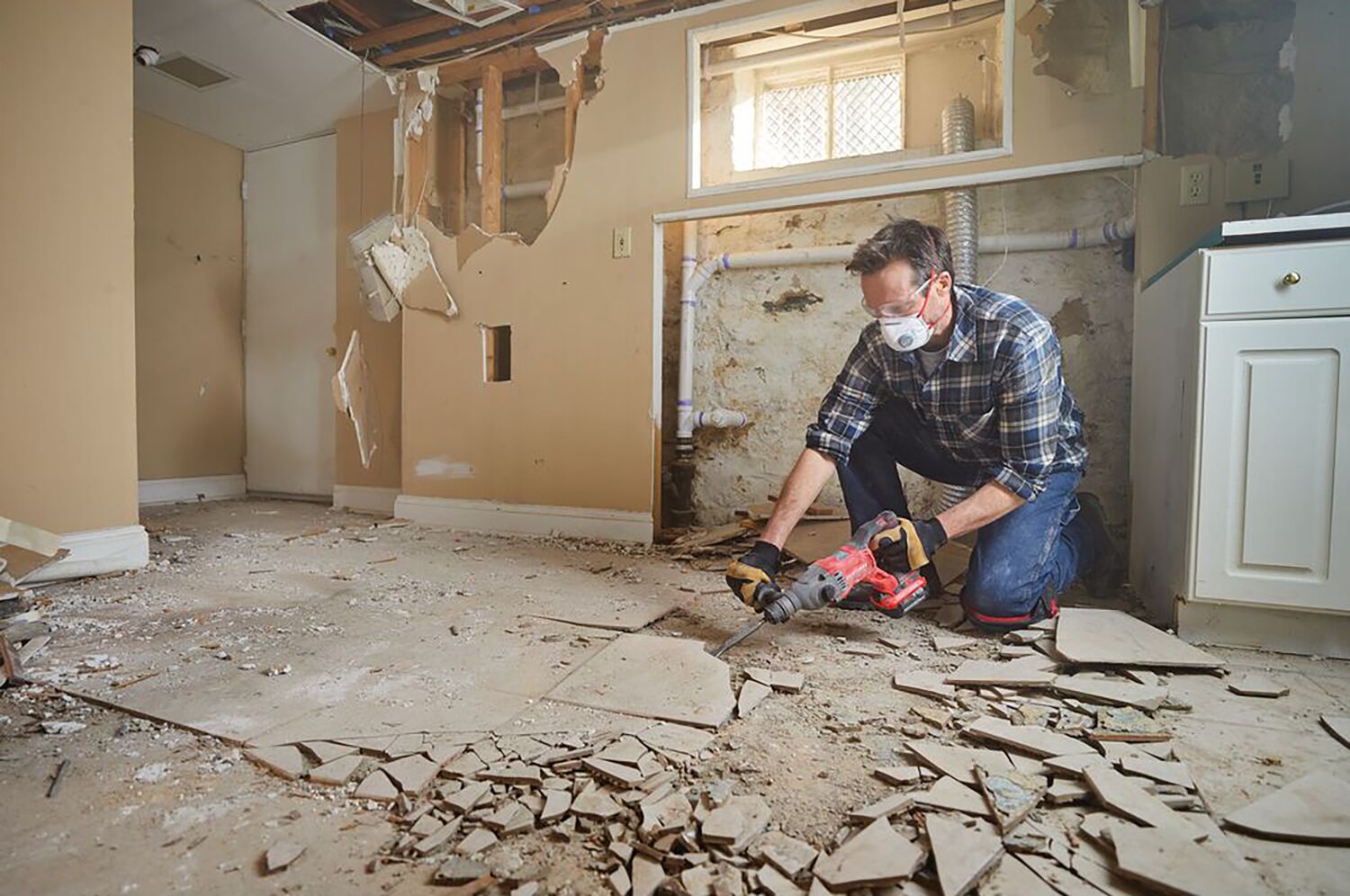 Man with gloves, respirator and safety glasses using the CRAFSTMAN V20 Brushless RP 7/8 inch SDS plus Rotary Hammer with to remove tile flooring.