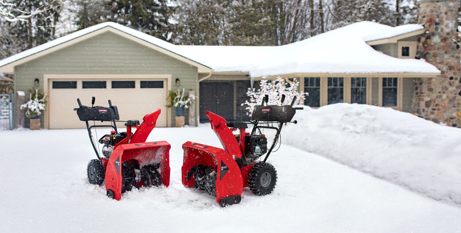CRAFTSMAN Gas Snow Blower with Push-Button Electric Start next to another CRAFTSMAN snow blower in front of a house